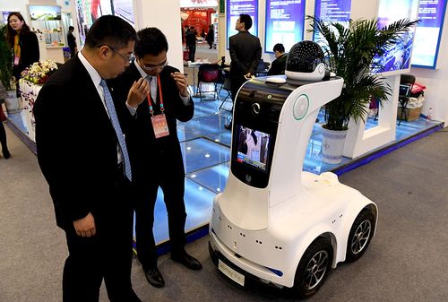 3月29日,参会展商在向客商介绍一款小区智能安保机器人产品.